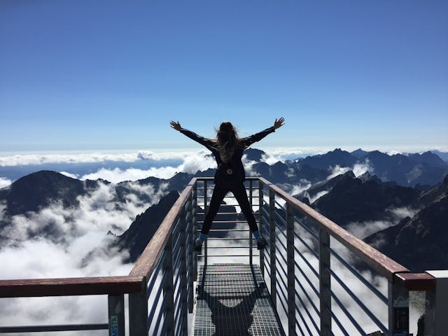 Memorable Vacation Spots - woman standing on the railings facing mountains