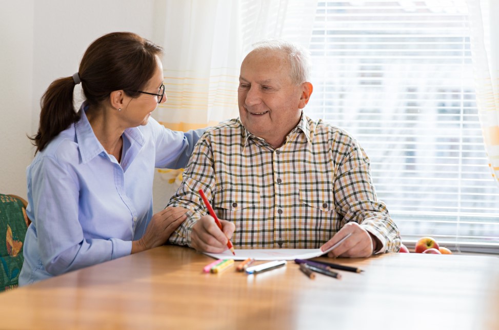 A photo of a woman showing support to a middle aged man who is suffering from young onset dementia