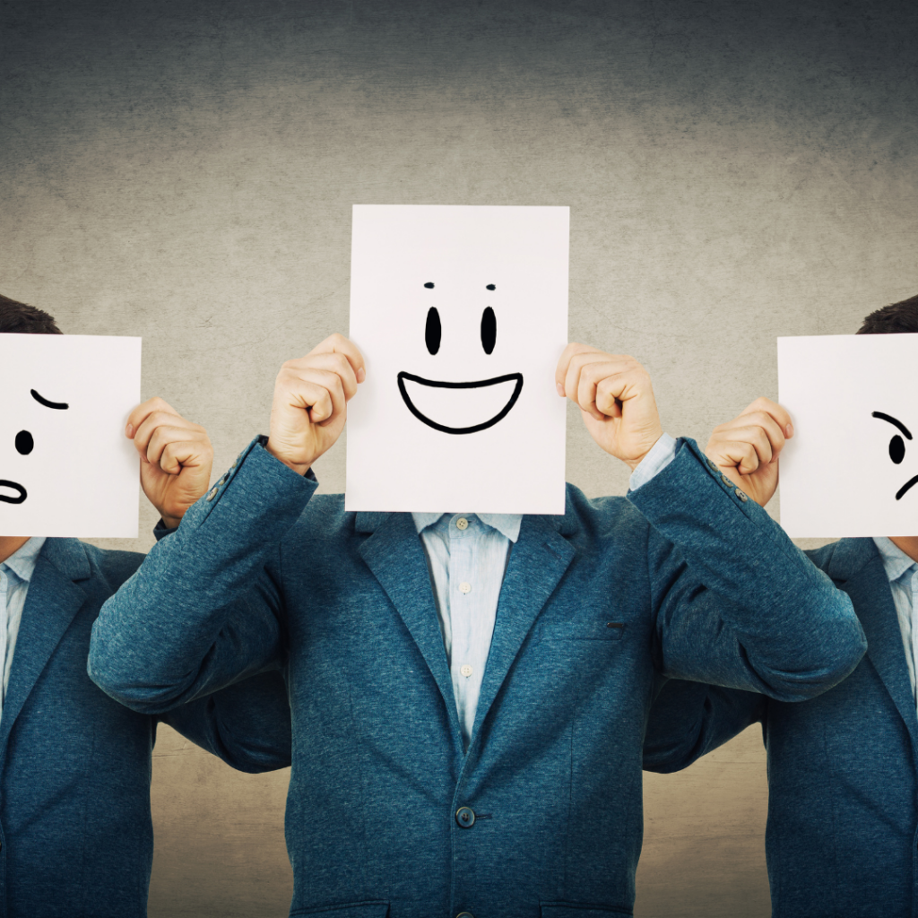 Picture of a man holding three different drawings in front of his face, symbolizing changes in mood or personality